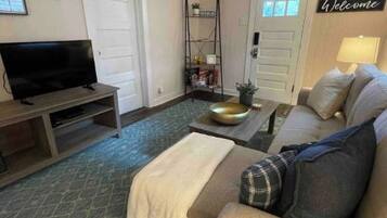 A living room with a sofa, a television, a coffee table, and a patterned rug.