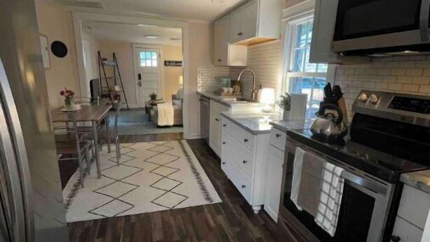 A modern kitchen with white cabinets, a stainless steel refrigerator, and a microwave. - Cheerful 2-bedroom Edenton bungalow getaway (Edenton)