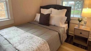 A bedroom with a bed, nightstand, and window. - Cheerful 2-bedroom Edenton bungalow getaway (Edenton)