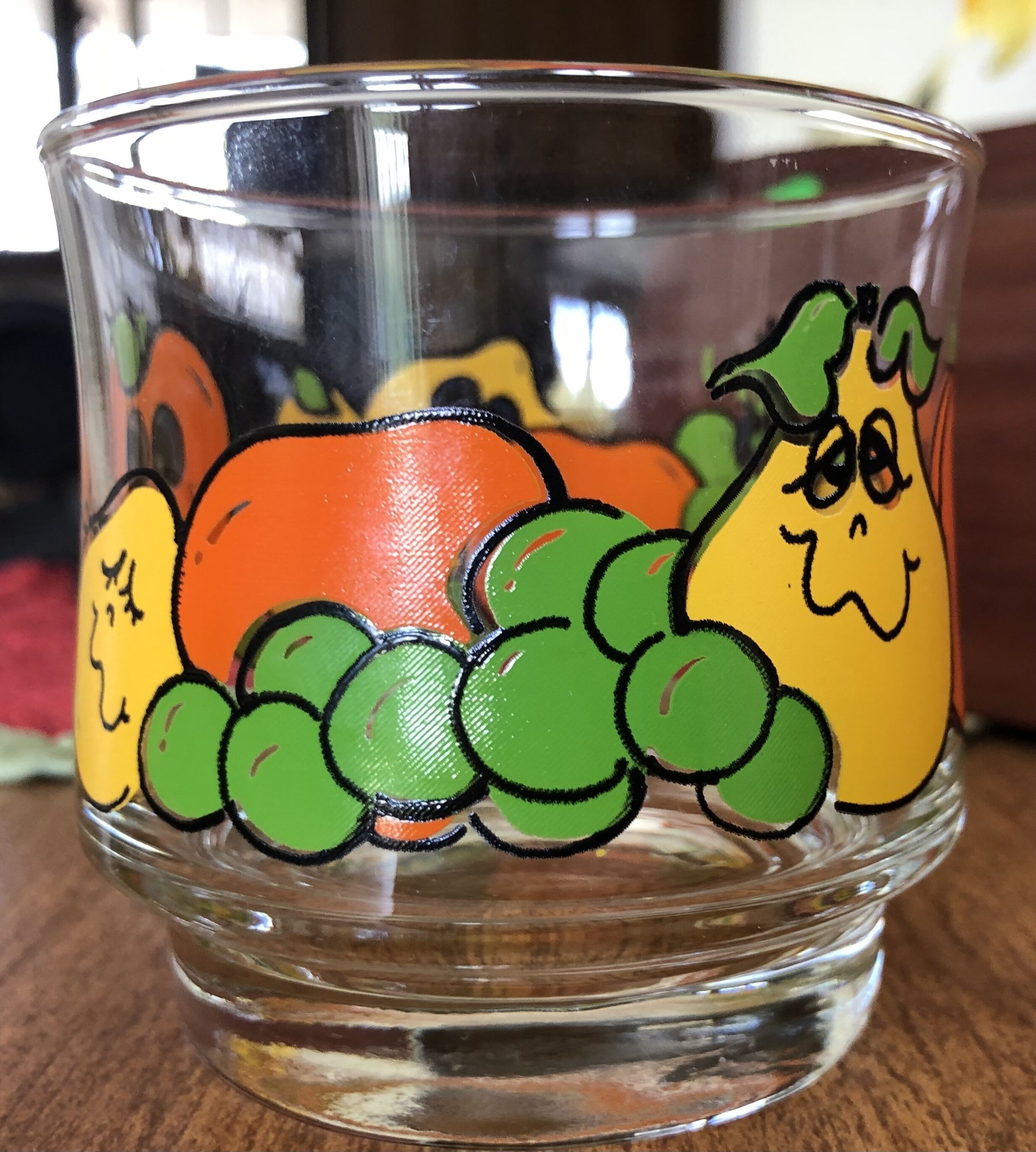 Un verre transparent orné d’un motif coloré représentant des légumes sur le côté.