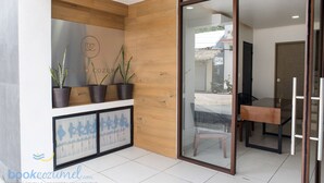 Un intérieur moderne avec un mur d’accent en bois, une porte en verre donnant sur un coin repas et des œuvres d’art encadrées accrochées au mur.
