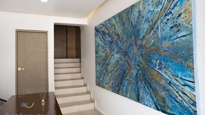 Un escalier menant à une pièce dont le mur est orné d’un grand tableau abstrait.