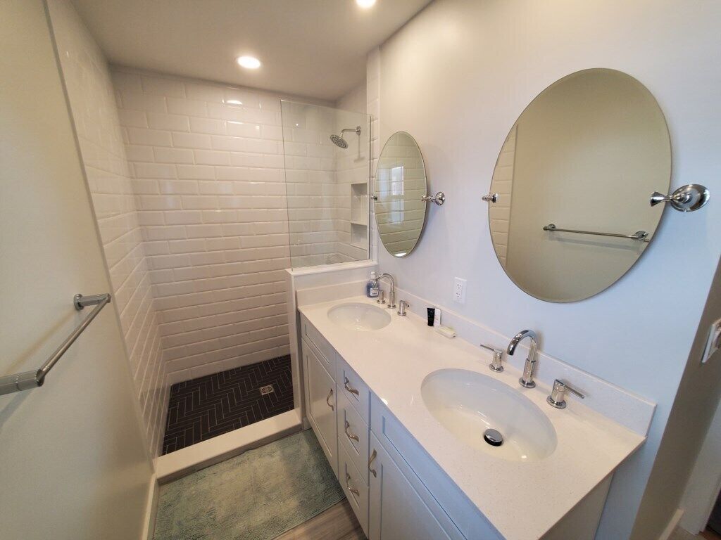 A bathroom with two sinks, a shower, and two mirrors.