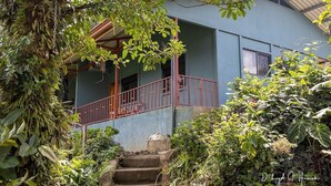 Un bâtiment à deux étages, doté d’un escalier à balustrade rouge menant à un porche abrité.