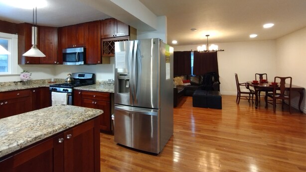 A spacious kitchen with wooden cabinets, a stainless steel refrigerator, and a dining area with a table and chairs.