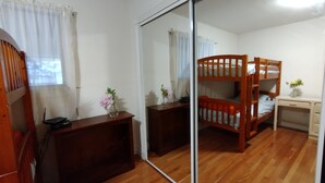 A room with a bunk bed, a desk, a mirror, and a dresser.
