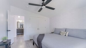 A bedroom with a bed, a ceiling fan, a nightstand, and a fireplace. - The Fortress (Cedar City)