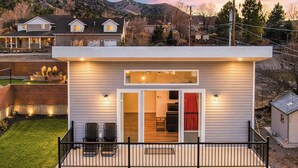 A modern single-story house with a covered patio, a garage, and a well-maintained lawn. - The Fortress (Cedar City)