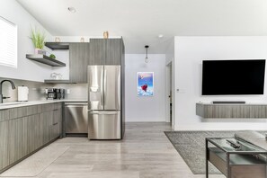 A modern kitchen with a stainless steel refrigerator, wooden cabinets, and a built-in oven.