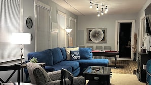 A living room with a blue sofa, a dining table with chairs, a ceiling fan, and a fireplace. - Experience Charleston charm near Hiwassee River (Charleston)