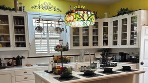 A kitchen with white cabinets, a central island with stools, a hanging chandelier, and a window with blinds. - Experience Charleston charm near Hiwassee River (Charleston)