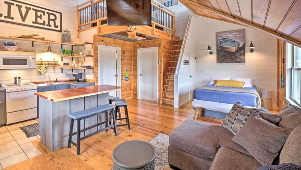 A cozy cabin interior with a kitchen, dining area, and a loft bedroom. - Updated Mtn View Studio w/ Loft - Near River! (Mountain View)