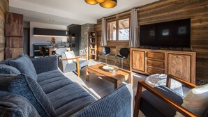 A modern living room with a large flat-screen TV, wooden cabinets, and a stone accent wall.