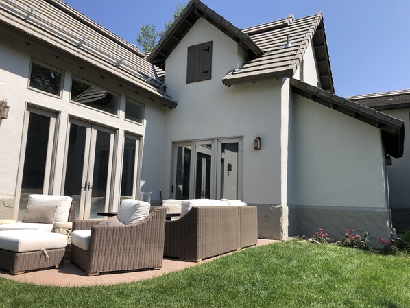 A house with a patio area featuring wicker furniture and a large sliding glass door.