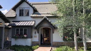 A two-story house with a stone foundation, a gabled roof, and a front entrance with a door and window. - Vail - Club at Cordillera Mountain Home with Exclusive Golf/Ski Privileges (Cordillera)
