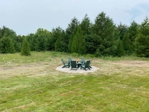 A grassy outdoor area with a circular arrangement of green chairs and a table, surrounded by trees. - Ellison Bay Family Retreat! 8 bed/6 bath/20 acres (Ellison Bay)