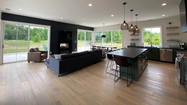 A modern kitchen with a large island, dark cabinetry, and a dining area with a high table and chairs. - Ellison Bay Family Retreat! 8 bed/6 bath/20 acres (Ellison Bay)