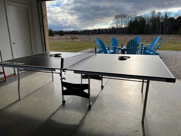 Une table de ping-pong avec des chaises, placée à l’extérieur d’un bâtiment.