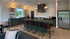 A modern kitchen with a central island, bar stools, and a refrigerator. - Ellison Bay Family Retreat! 8 bed/6 bath/20 acres (Ellison Bay)