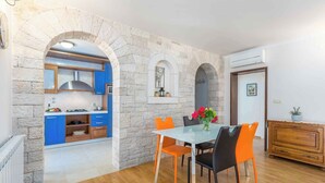 Una cocina moderna con armarios azules, un arco de piedra y una zona de comedor con sillas color naranja.