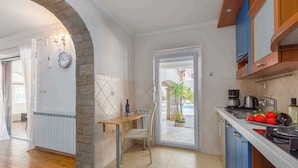 Una cocina moderna con un arco de piedra, una zona de comedor con una mesa y sillas, y vistas al exterior a través de un ventanal.