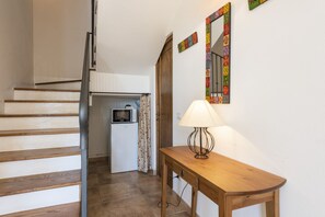 A staircase leading to a kitchen area with a microwave, a wooden table with a lamp, and a mirror with a colorful frame. - Villa Clemente by MMega (Lucignano)