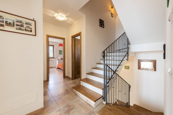 A staircase with wooden steps and black railings, leading to a landing with a light fixture.