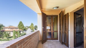 Un balcon avec un mur en briques, un sol carrelé et une vue sur des maisons et des arbres.