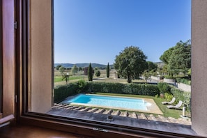 Une piscine offrant une vue sur un jardin aménagé et sur des collines lointaines.