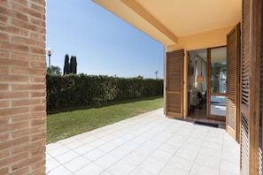A patio area with a tiled floor, a brick wall, and a hedge.