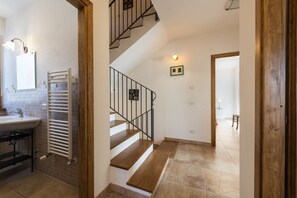 Eine Treppe, die zu einer zweiten Etage führt, ein Badezimmer mit Waschbecken und Handtuchhalter sowie ein gefliester Boden.