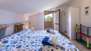 Une chambre à coucher avec un lit, une table de chevet, une lampe, une armoire et une vue sur l’extérieur.