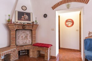 Une pièce avec une cheminée en briques, un banc rouge, un tableau encadré et un miroir au mur.