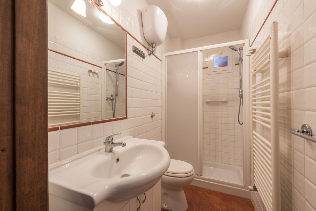 Bagno con lavandino bianco, wc e doccia a filo pavimento.