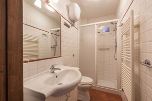 Un baño con lavamanos blanco, inodoro y cabina de ducha.