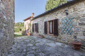 Un bâtiment en pierre doté d’une cour, de plantes en pot et d’une décoration en treillis.