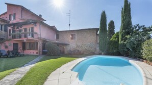 Uma casa com piscina, jardim e um edifício de pedra.