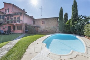 A house with a swimming pool, a garden, and a stone building.