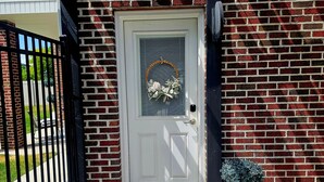 Ein Backsteinhaus mit einer weißen Tür, einem schwarzen Tor und einem Blumentopf.