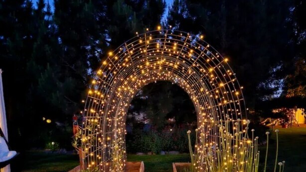 Un arco iluminado en un jardín al anochecer.