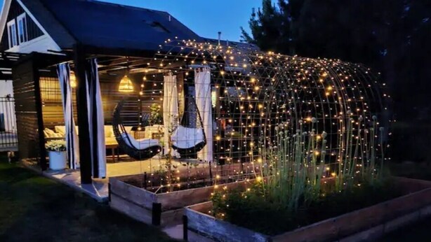 Ein Haus mit überdachter Veranda, einer Hängematte und einem Garten mit Lichterkette.