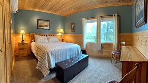 A bedroom with a bed, bedside lamps, a bench, a desk, and a window with curtains. - Spacious 3 bedroom 2 bath lodging near trails, with lots of off-street parking! (Ely)