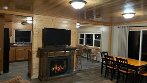 A cozy cabin interior with a fireplace, wooden furniture, a television, and a dining area. - Spacious 3 bedroom 2 bath lodging near trails, with lots of off-street parking! (Ely)