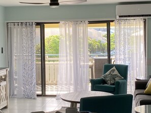 Relax in this stylish living room with a balcony, featuring a sofa, armchair, and coffee table.
