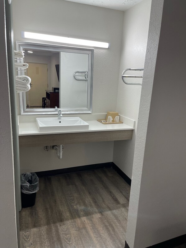 A bathroom with a white sink, a large mirror, and a towel rack.