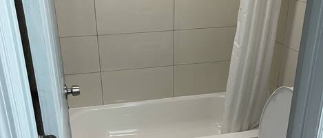A bathroom with a bathtub, toilet, and a shower curtain.