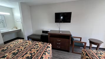 Een hotelkamer met twee bedden, een bureau, een stoel, een televisie en een tafeltje.