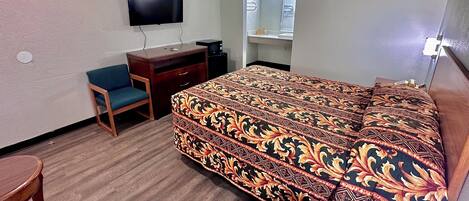 Ein Hotelzimmer mit Bett, Schreibtisch, Sessel, Fernseher und Fenster.