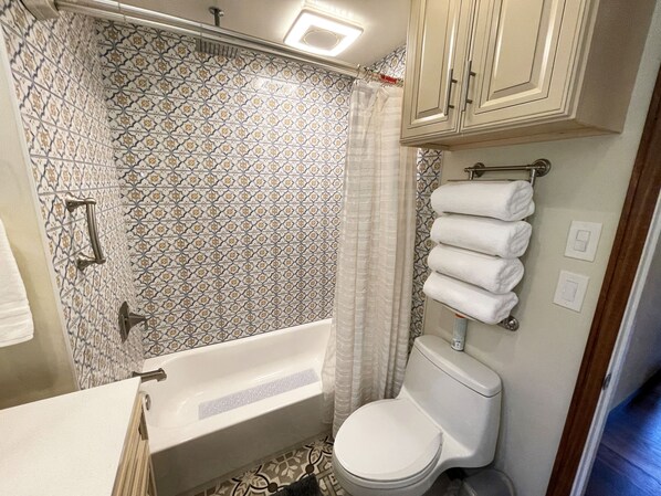 A bathroom with a bathtub, toilet, and shower curtain.