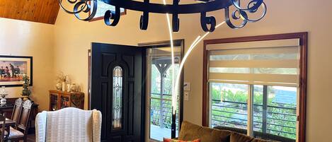 A cozy living room with a chandelier, a black door, a brown sofa, and a white armchair.